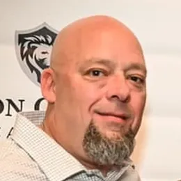 A bald man with a beard is smiling for the camera.