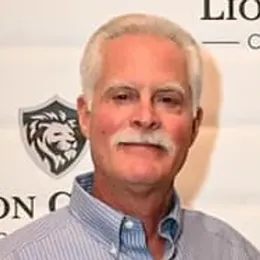 A man with a mustache is wearing a striped shirt and posing for a picture.