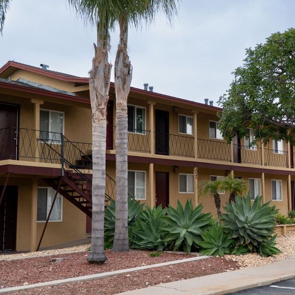 A large apartment building with palm trees in front of it