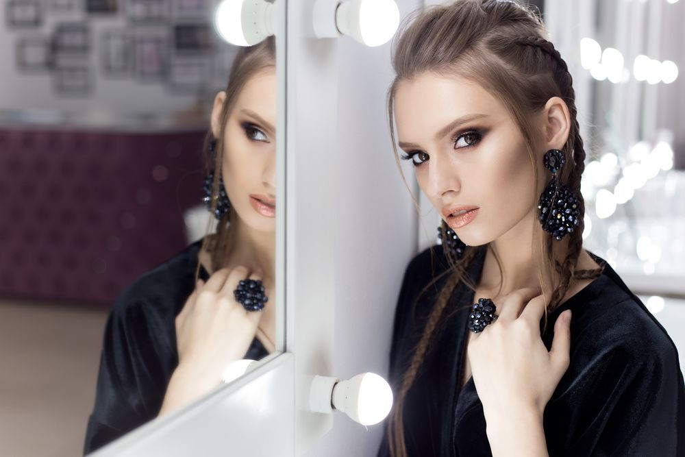 A Woman is Standing in Front of a Mirror Looking at Her Reflection — K. Smith & Son Jewellers In Caloundra, QLD