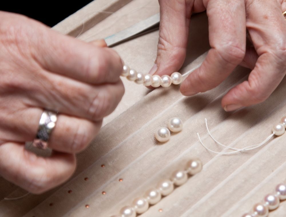 A Person is Working on a Pearl Necklace With a Ring on Their Finger — K. Smith & Son Jewellers In Caloundra, QLD