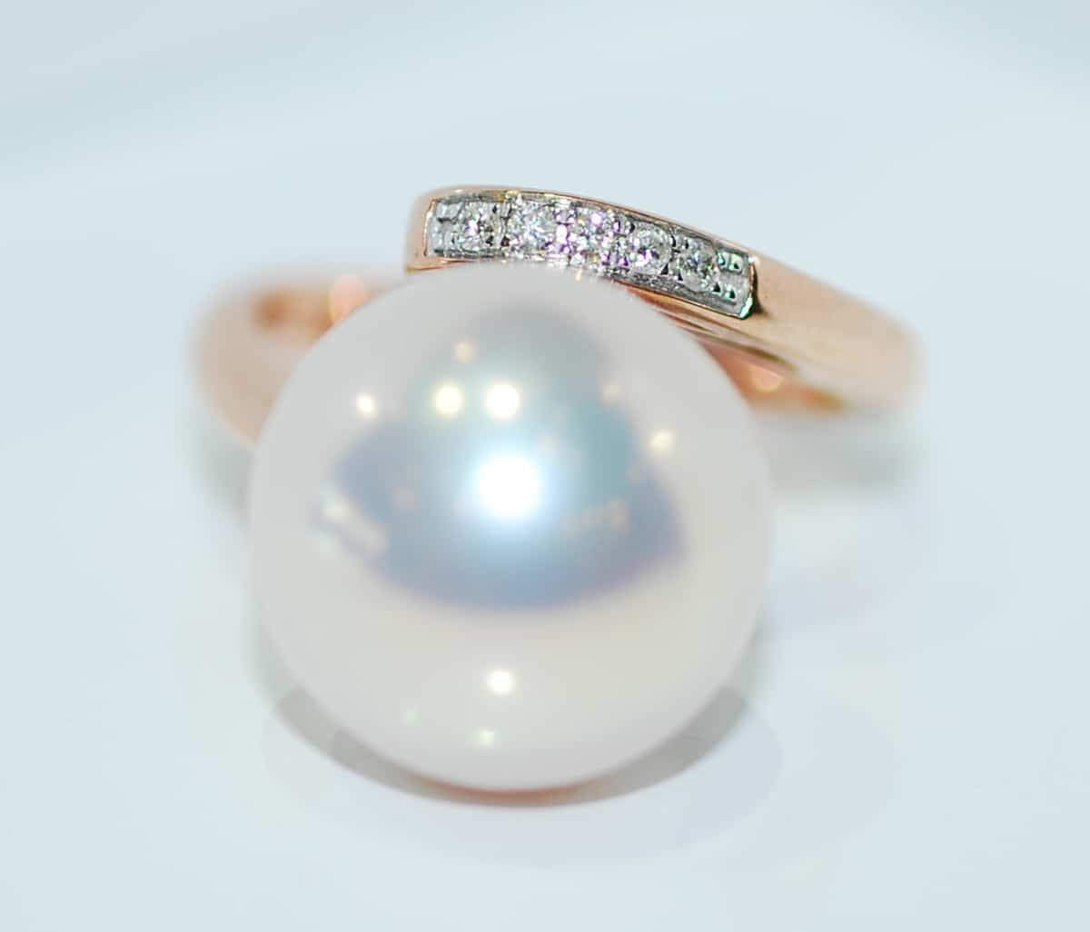 A rose gold ring with a large white pearl and a band with small diamonds on a white surface — K. Smith & Son Jewellers In Caloundra, QLD