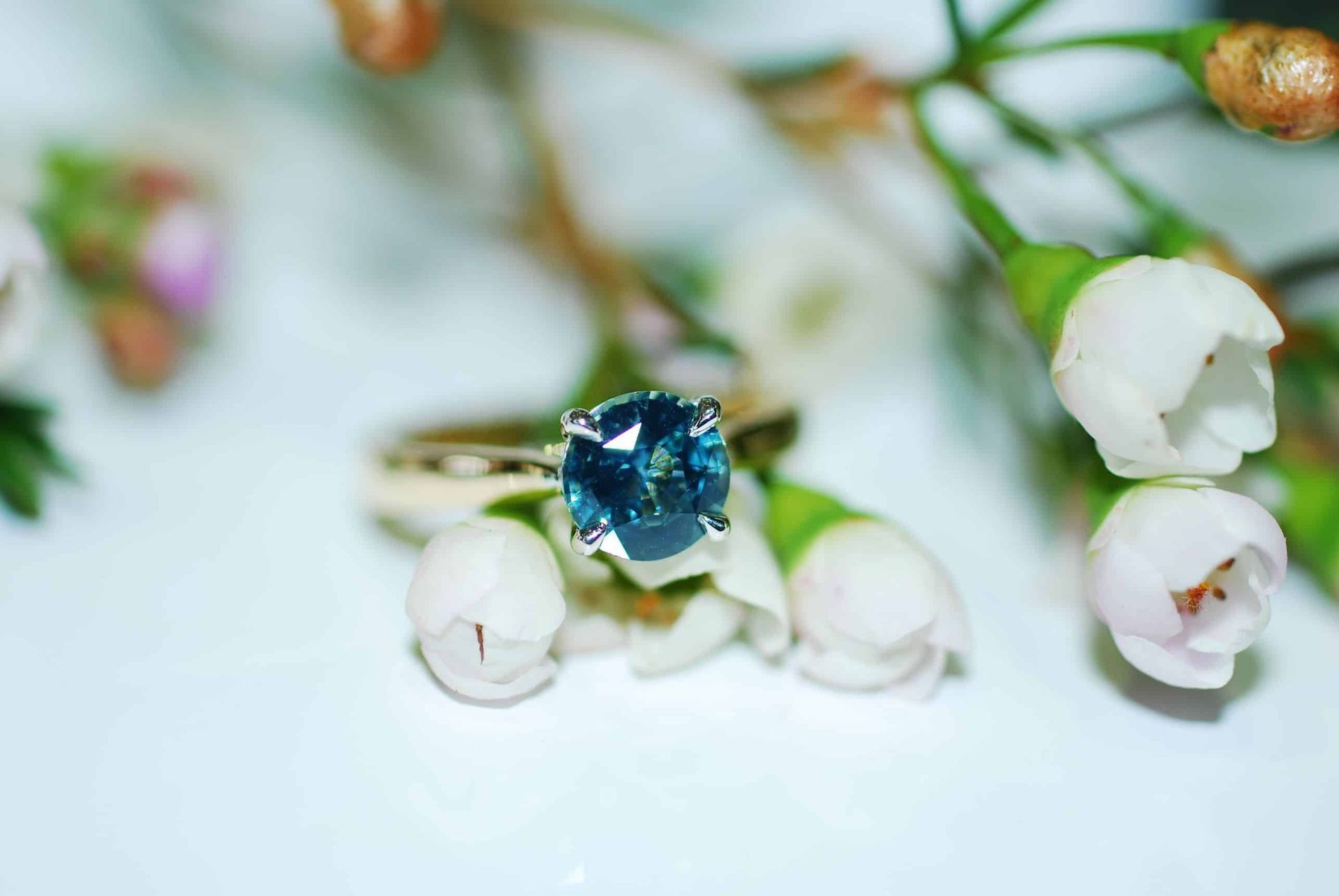 A Close Up of a Ring With a Blue Stone Surrounded by White Flowers — K. Smith & Son Jewellers In Caloundra, QLD
