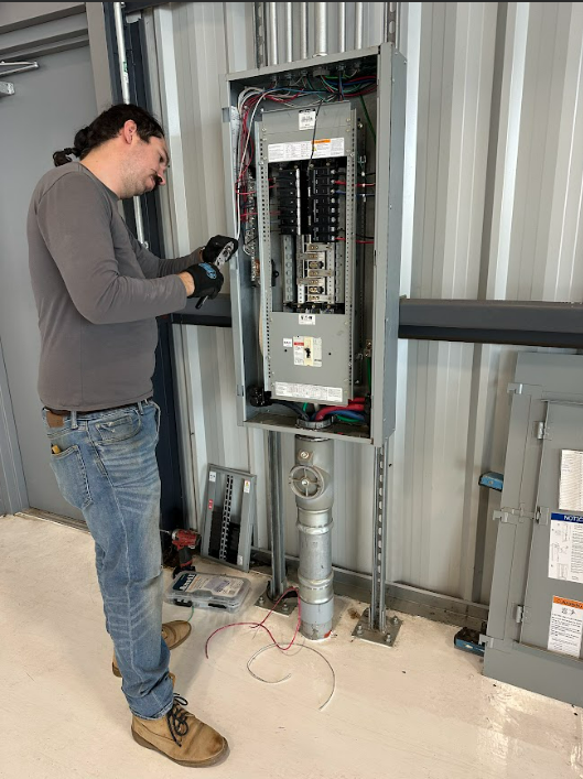 A man is working on an electrical box in a building.