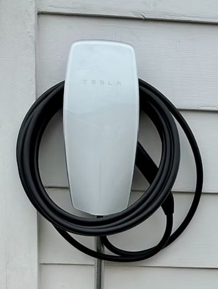 A white tesla charging station with a black cable attached to it