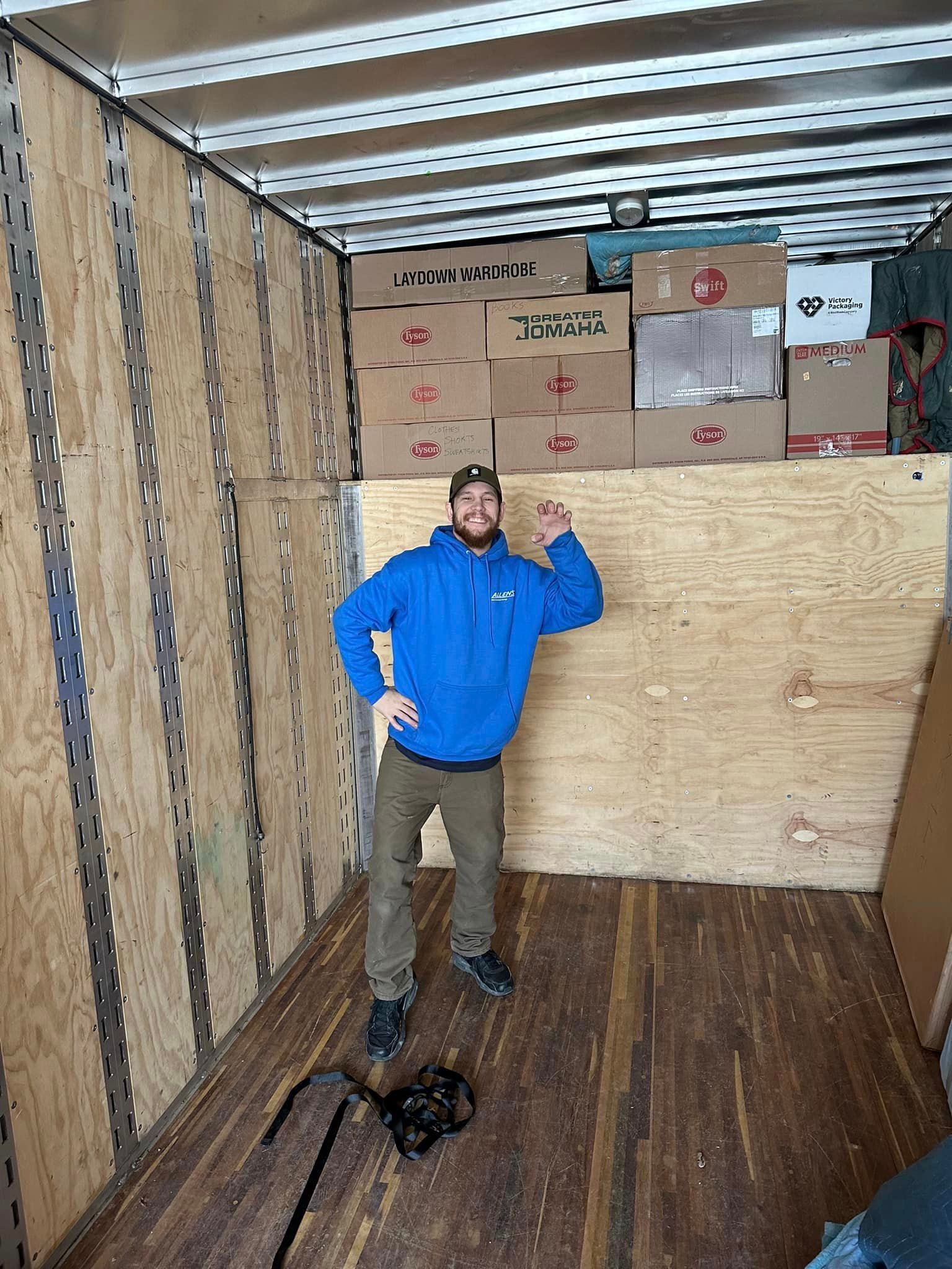 A man is standing in the back of a moving truck.