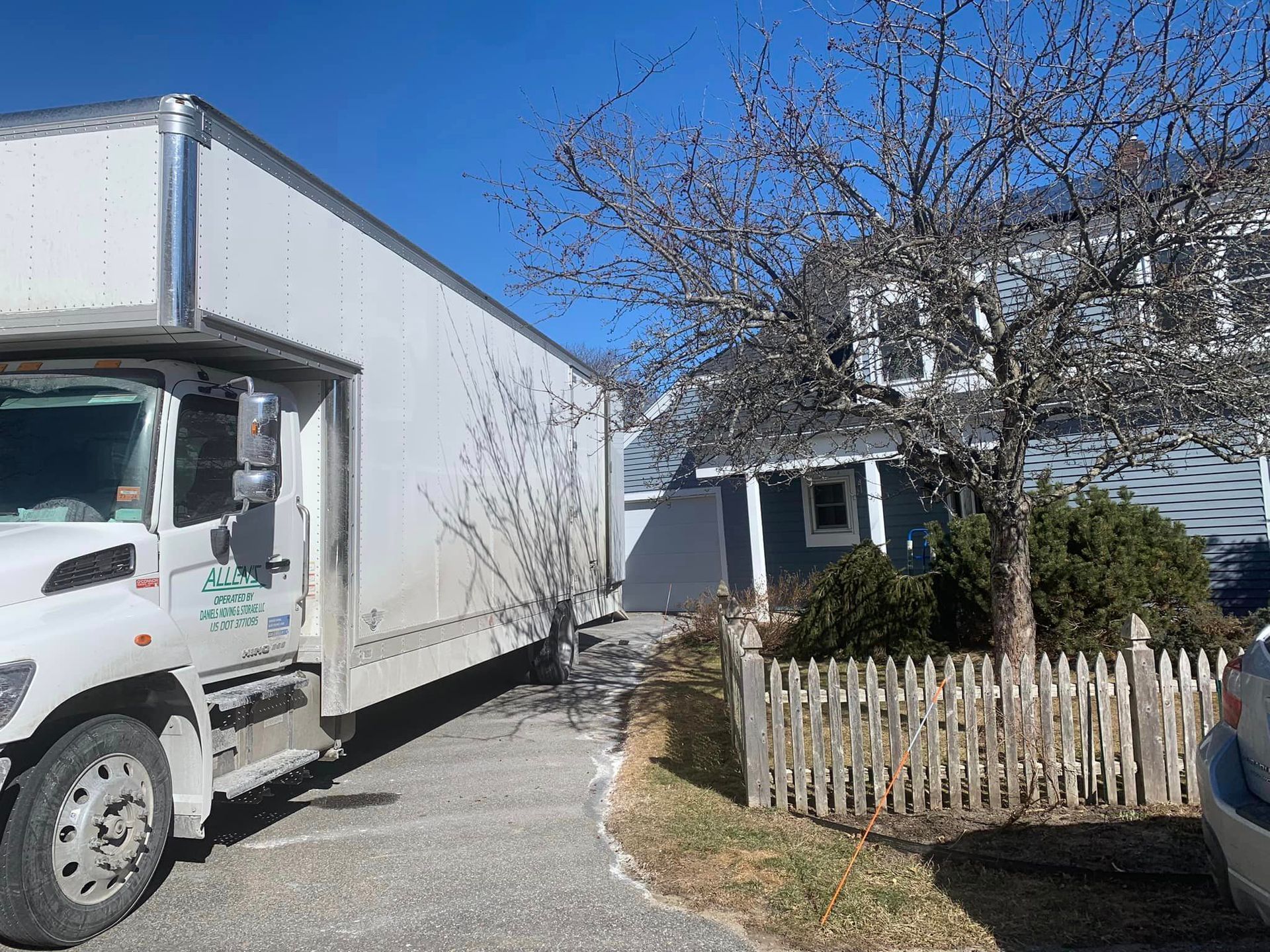 A white moving truck is parked in front of a house.