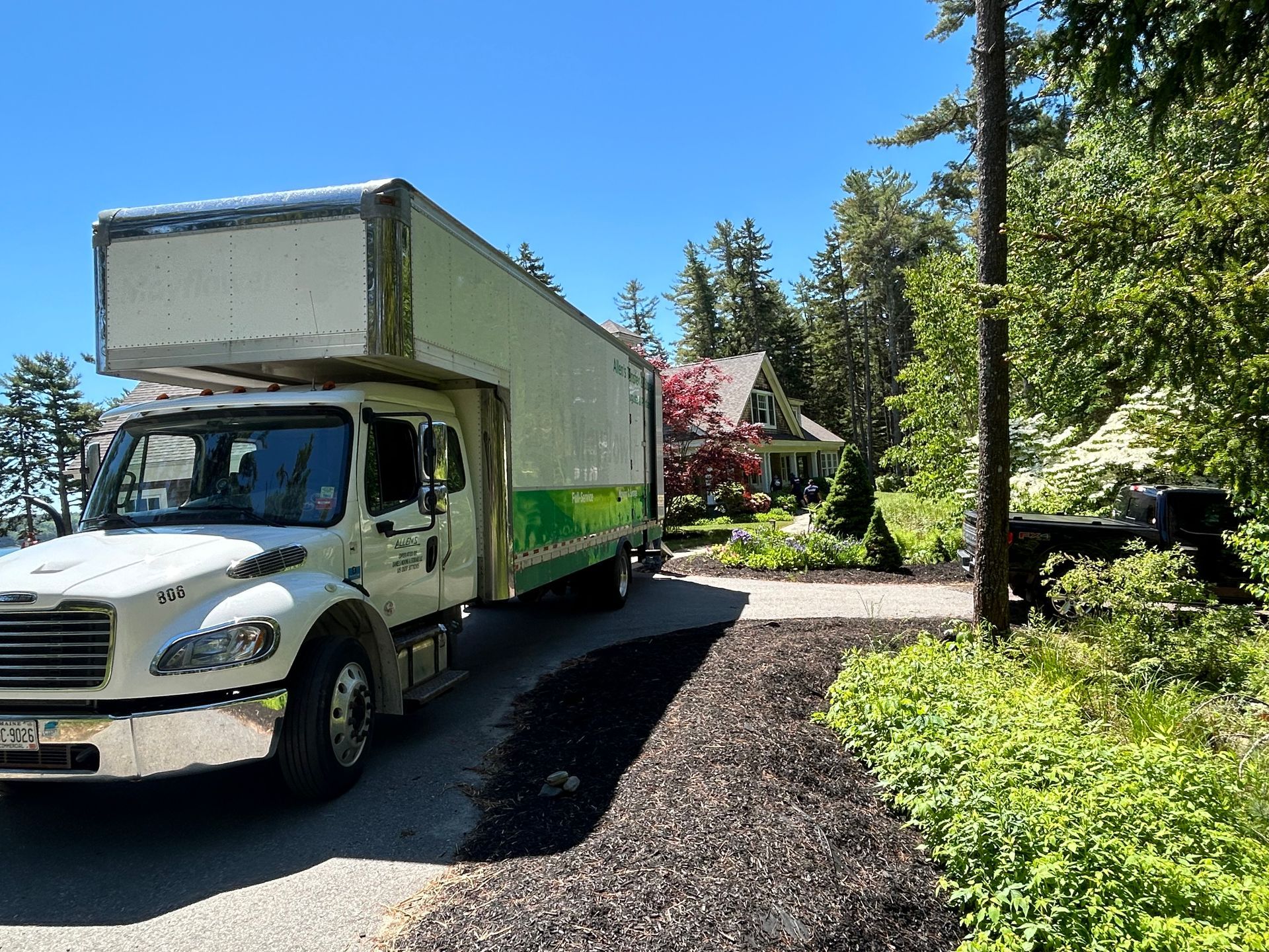 A moving truck is parked on the side of the road in front of a house.