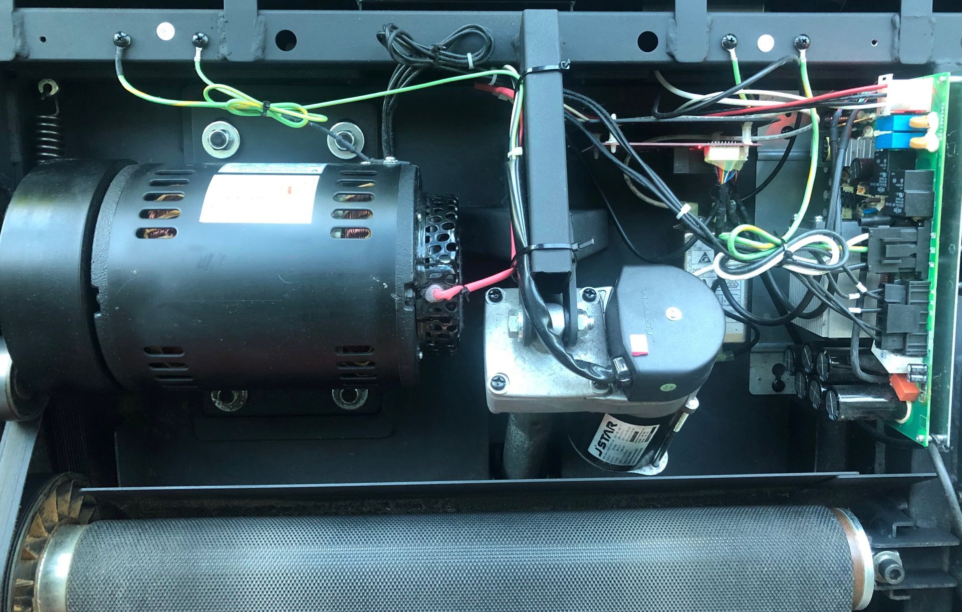 Internal components of a treadmill, including a motor, control board, and wiring.