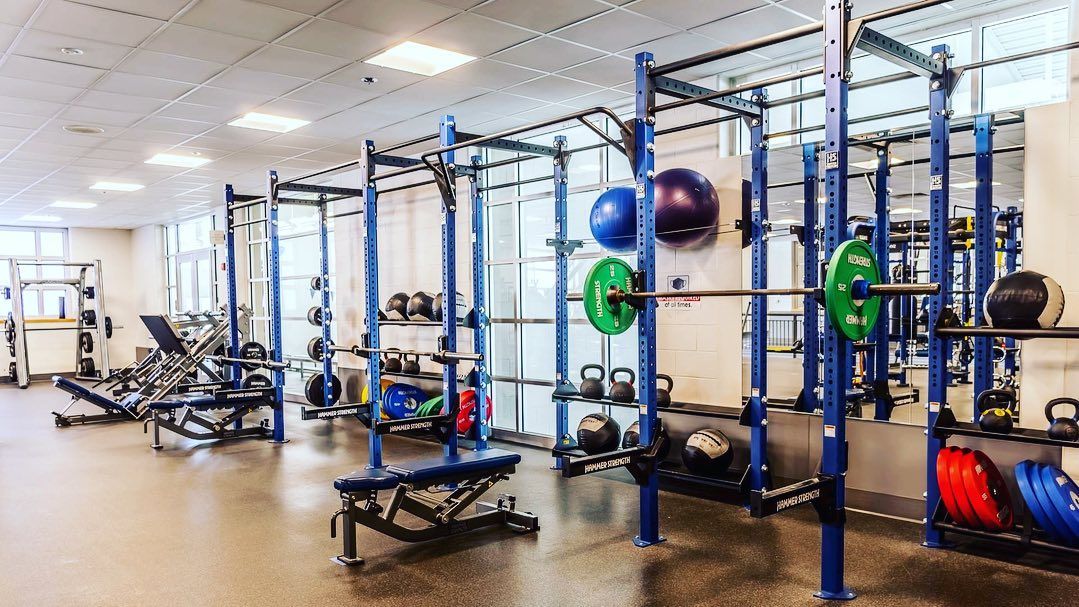 Gym with blue weight racks, barbells, weights, and exercise equipment.
