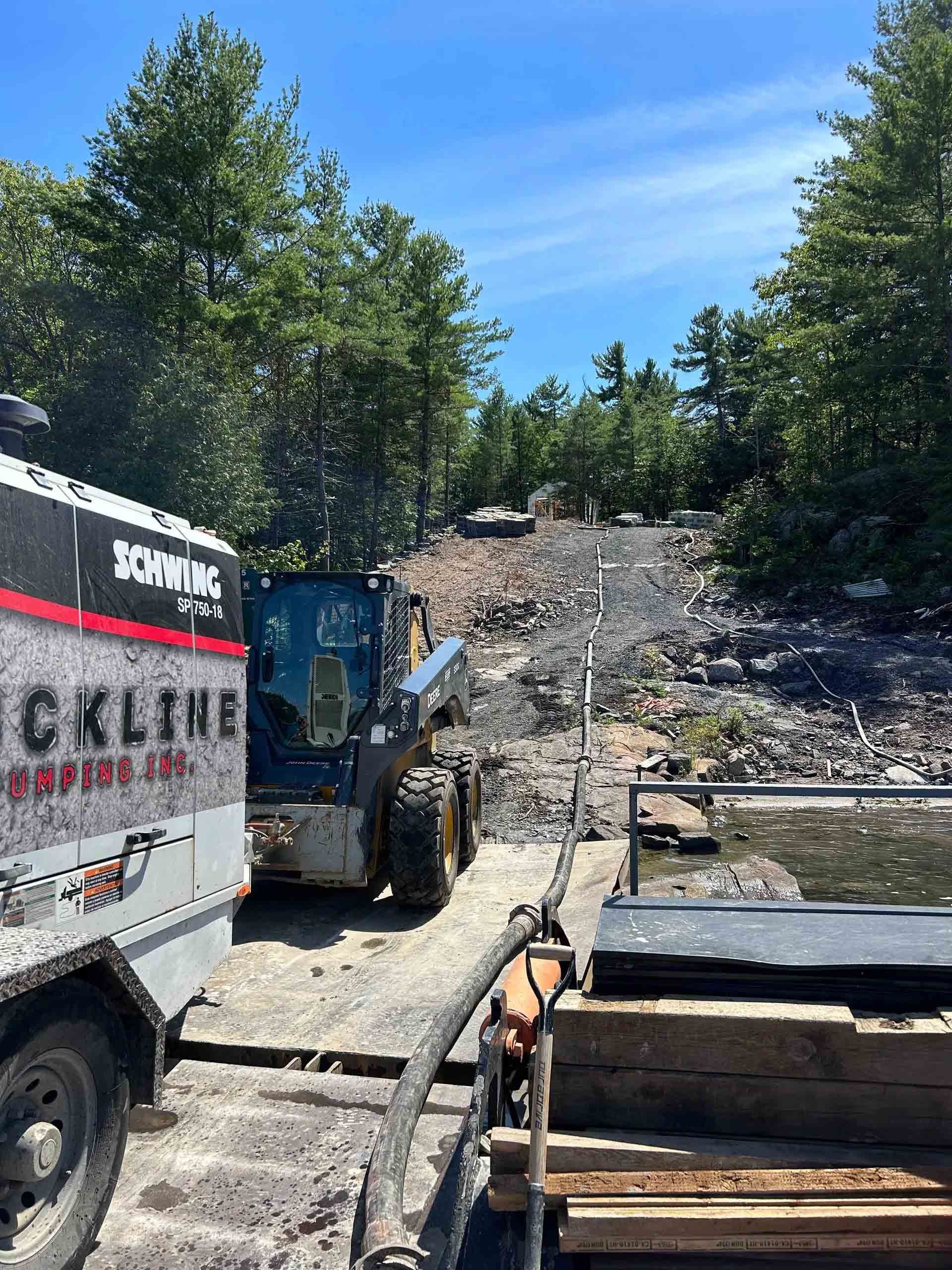 Construction equipment clearing debris on a rocky hillside under a blue sky