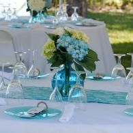 Blue and white floral centerpiece on a decorated outdoor table with turquoise accents