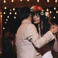 Couple dancing closely at a dimly lit event, with warm string lights in the background.