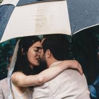 Couple embracing and kissing under a white umbrella in the rain
