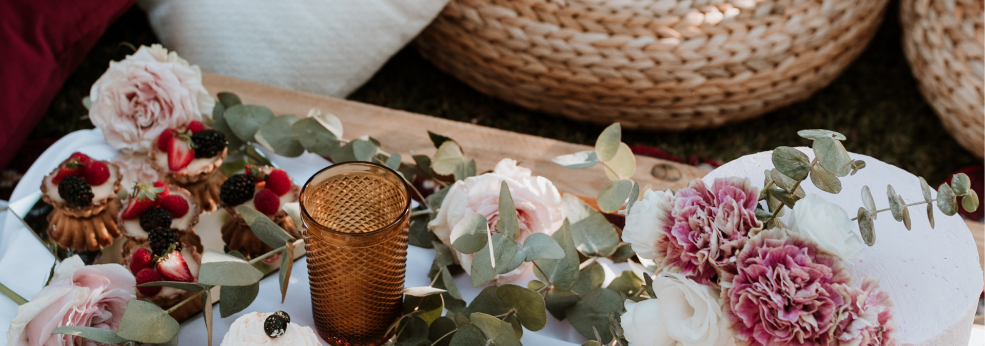 Dried floral arrangement with pink and white flowers, greenery, and a gold candle on a table