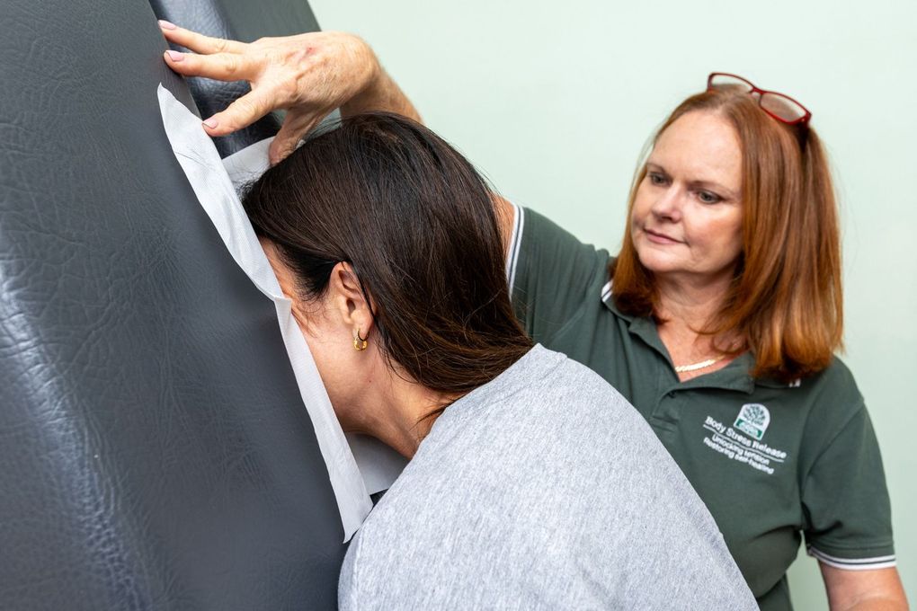 Woman giving a foot massage to a client on a treatment table in a bright room