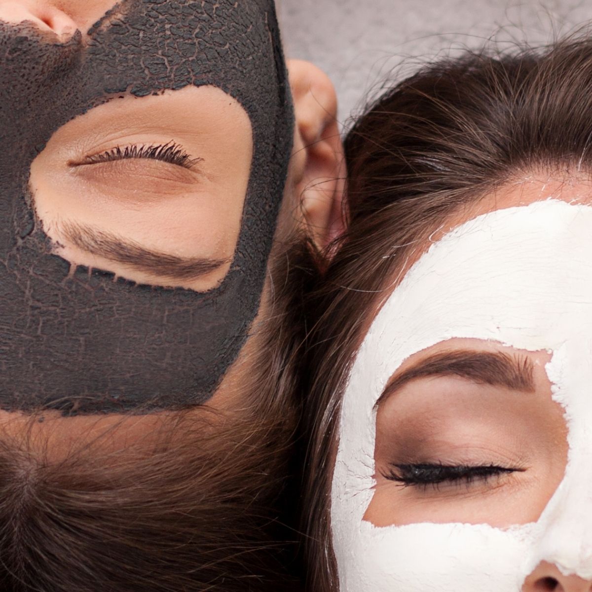 Two people lying side by side with black and white facial masks, eyes closed
