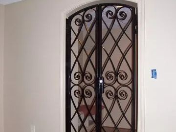 Wrought iron double doors with decorative scrollwork within a light-colored doorway.