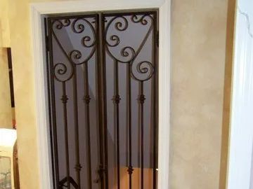 Black wrought iron security door with ornate swirls, set in a white door frame.
