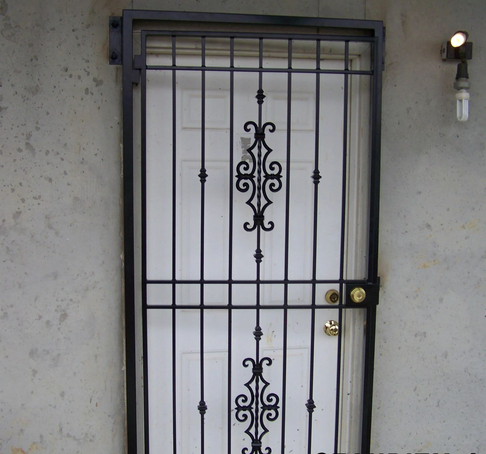 Black metal security door over a white door.