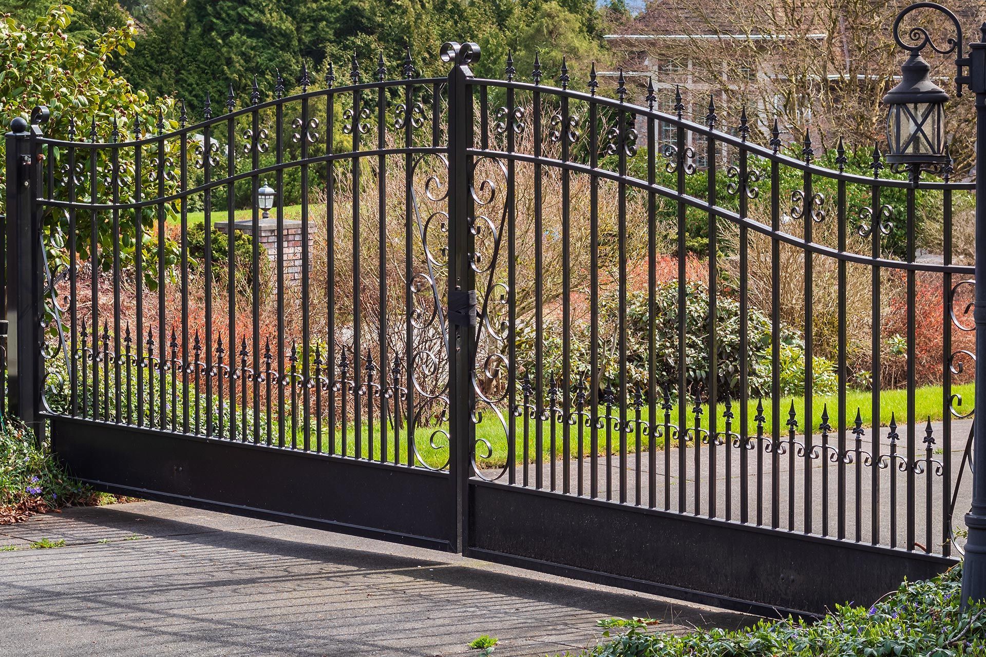 Elegant wrought iron estate gate frames landscaped upscale entry. Elegant wrought iron estate gate frames landscaped upscale entry.