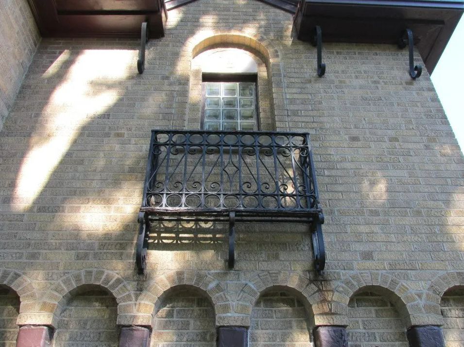 Brick building facade with a small iron balcony and arched details.