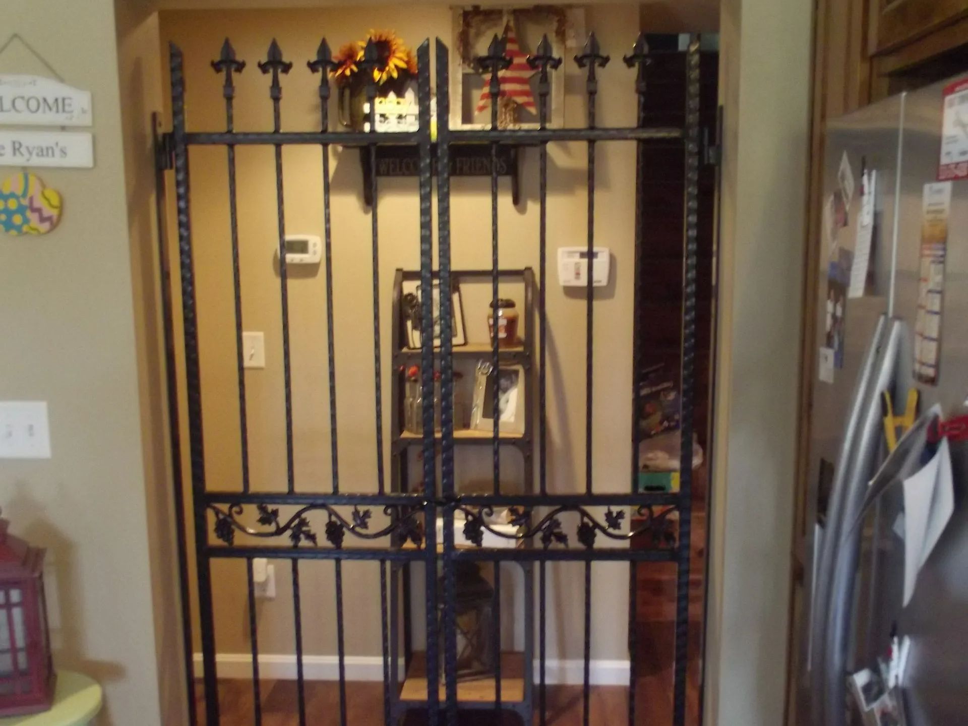 Black wrought iron gate in doorway, decorated with fleur-de-lis and leaves; beige walls.