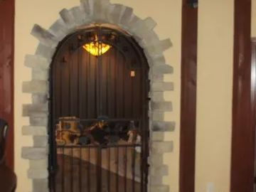 Arched doorway with stone frame and black metal gate. Interior view with wood accents and warm lighting.