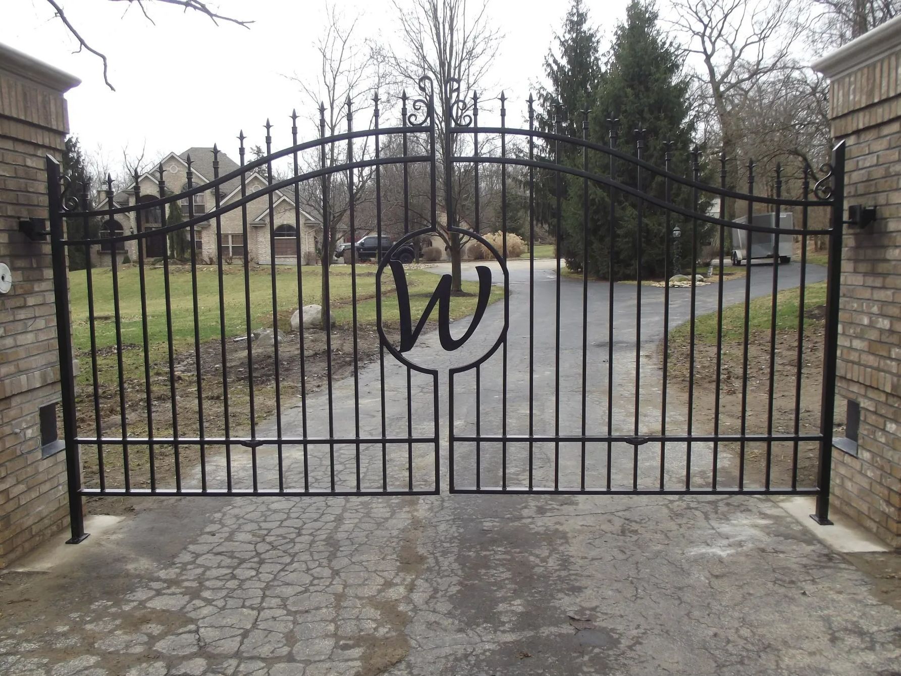 Black wrought iron driveway gate with a large 