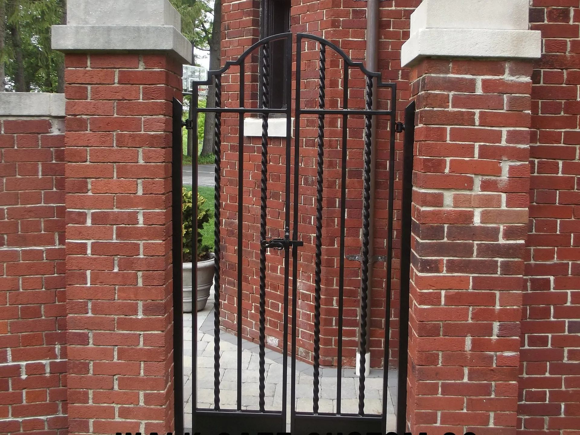 Black metal gate set between brick pillars.