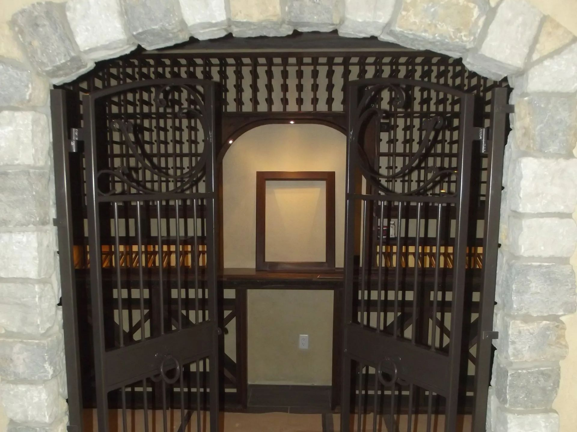 Wine cellar entrance with stone archway, ornate iron gates, and wooden wine racks.
