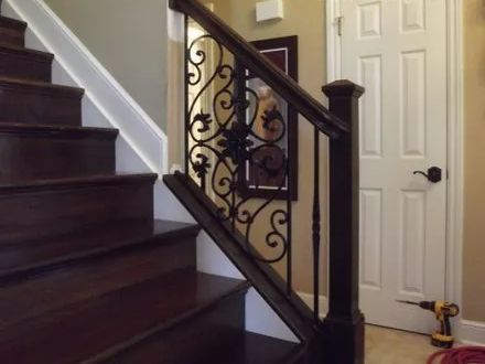 Dark wood staircase with wrought iron railing, white trim, and a closed white door.