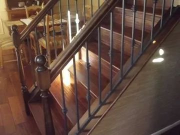 Wooden staircase with dark metal spindles and a wooden banister.