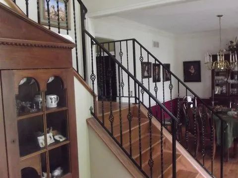 Staircase with wrought iron railing, wooden steps, and a wooden cabinet.