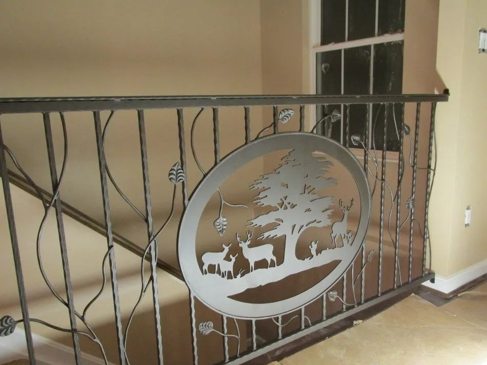 Metal railing with a cutout oval scene of deer under a tree.