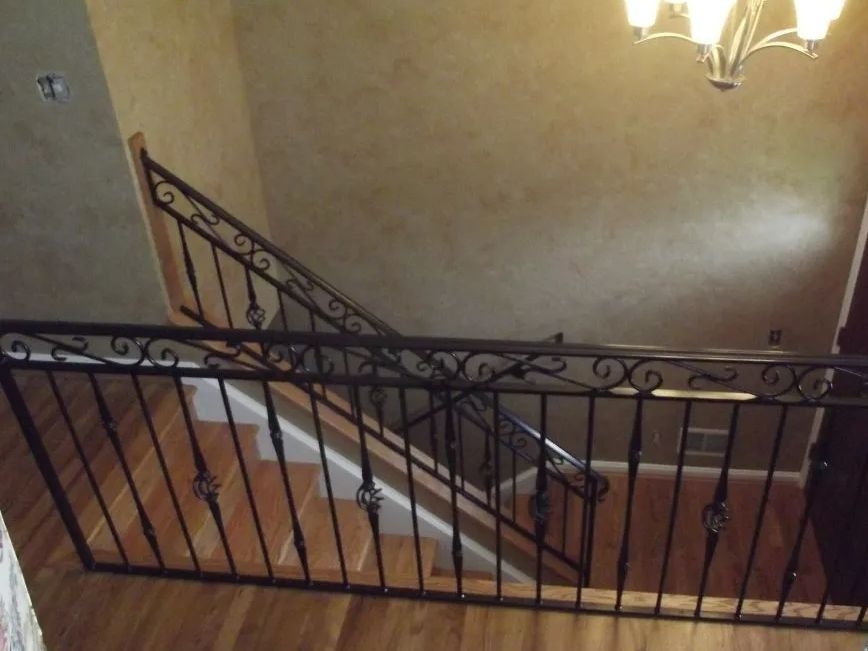 Wrought iron railing and staircase with wooden steps and flooring, view from above.