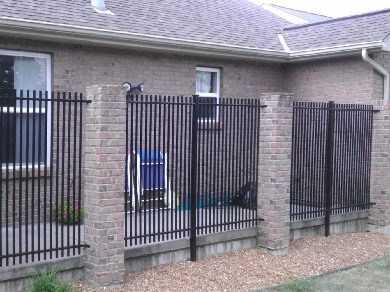 Black metal fence sections between brick columns along a building's wall.