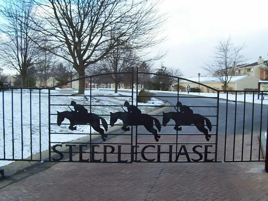 Black iron gate with silhouettes of three horses and riders; 