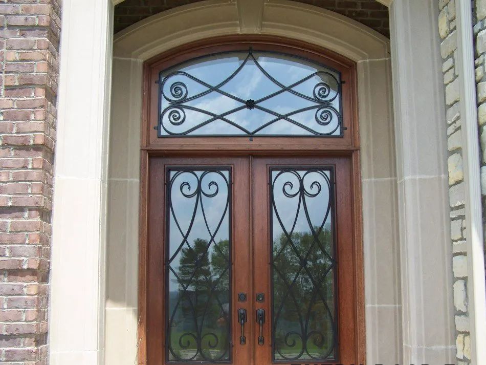 Wooden double doors with decorative ironwork, arched transom window.