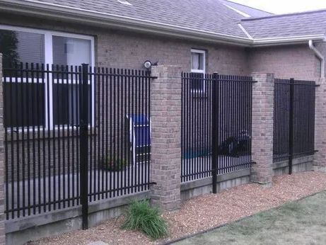 Black metal fence section attached to a brick building.