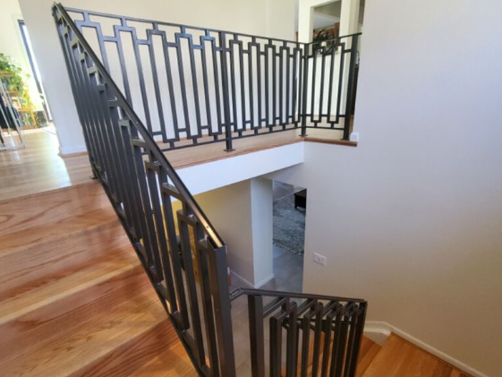 Metal railing on a wooden staircase leading to a landing with matching railing.