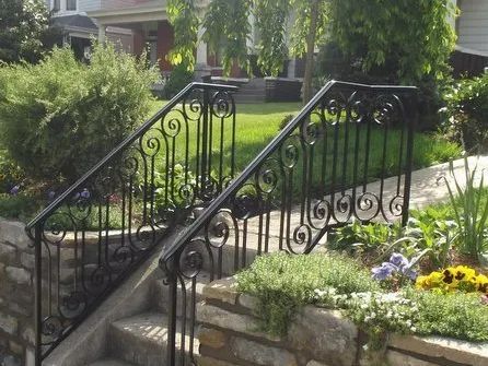 Black wrought-iron railing along stone steps leading to a grassy yard.