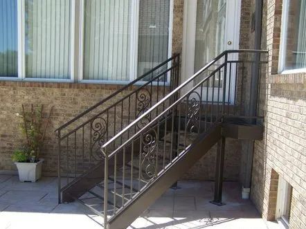 Outdoor staircase with brown metal railings and brick exterior.