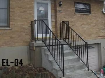 Concrete steps leading to a door with black metal handrails; brick building exterior.