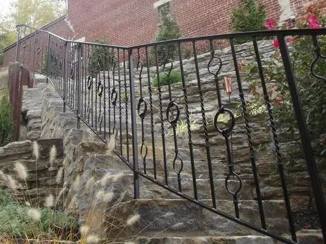 Stone steps with wrought iron railing leading uphill. Brick building in background.