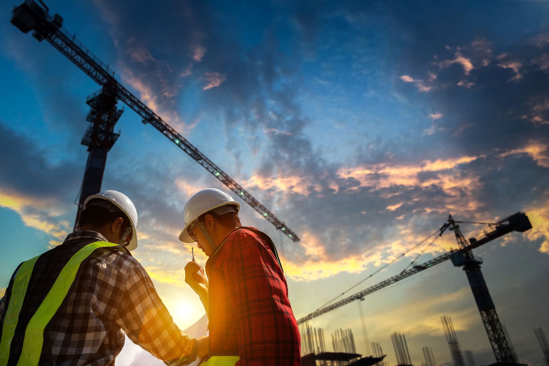 Two construction workers are looking at a blueprint at a construction site.