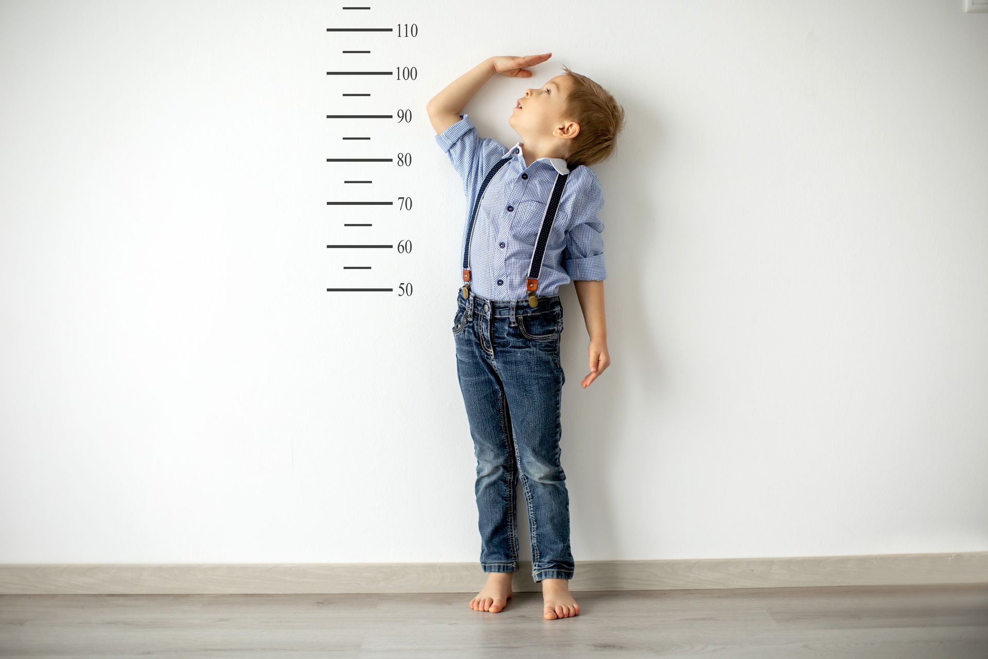 Little boy standing against a wall to measure is height
