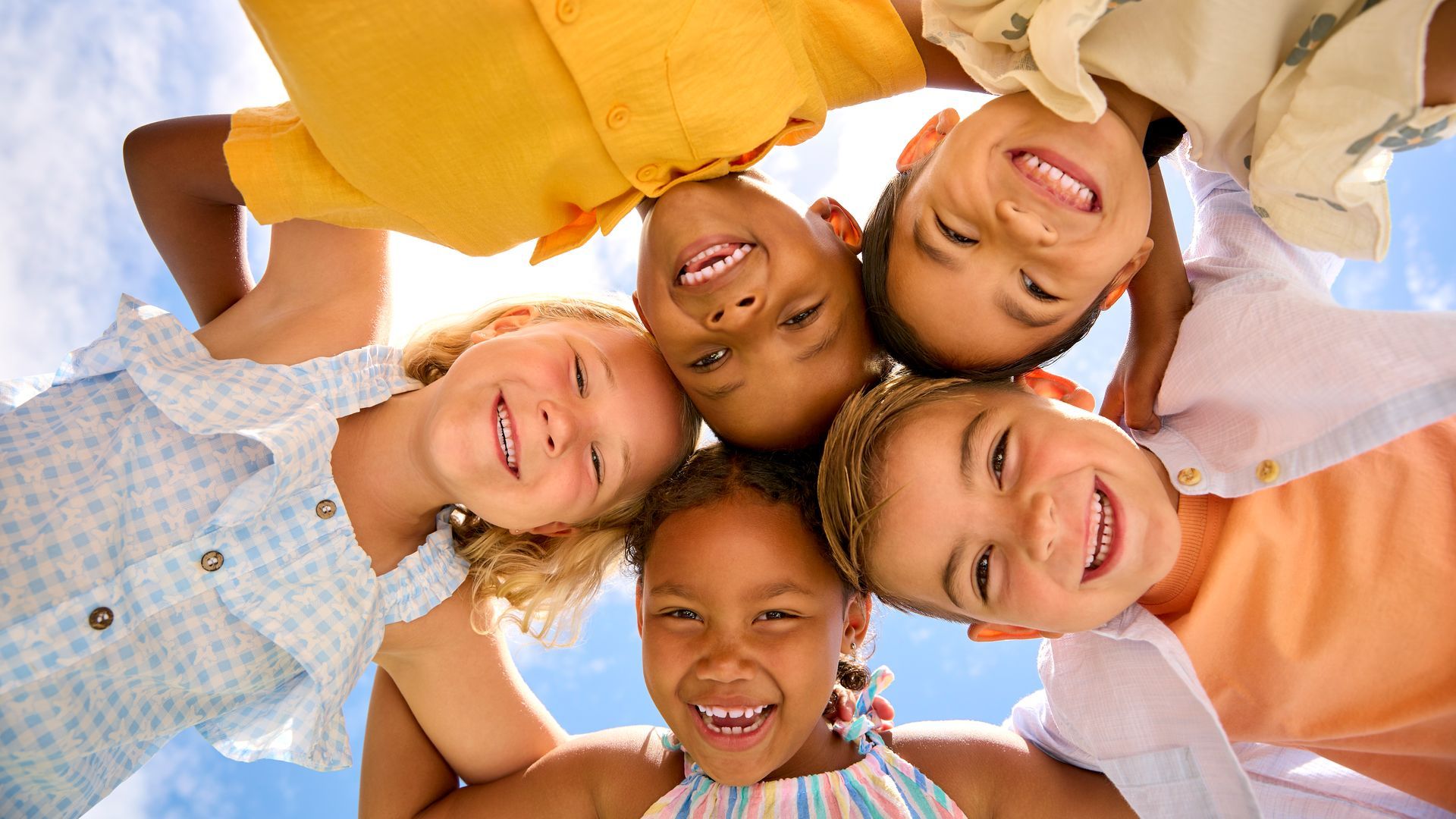 Group of children in a circle looking down at the camera