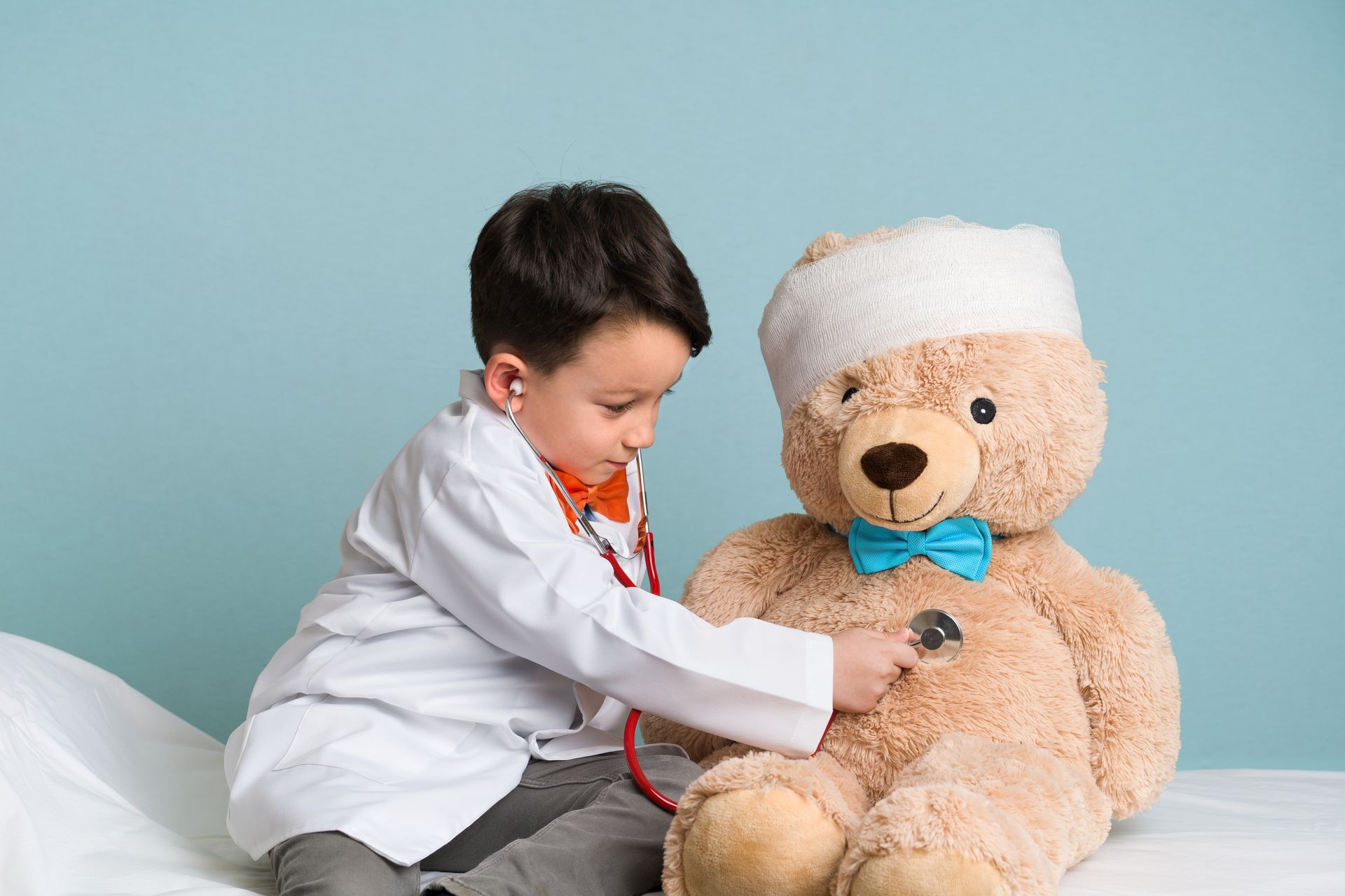 Little boy listening to the heartbeat of a teddy bear with a stethoscope