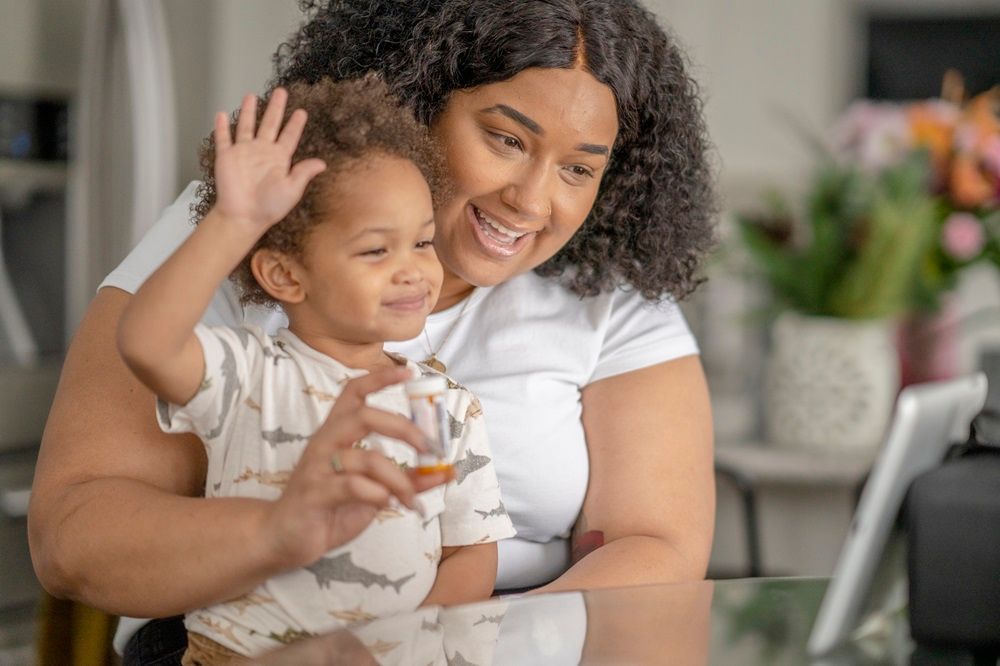 Mom and toddler waving to someone on their computer